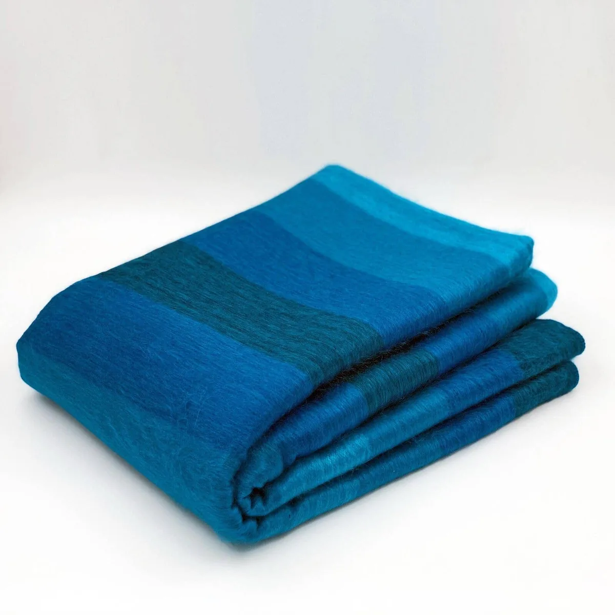 Gefaltete ECUALAMA Decke mit blau-türkisen Streifen